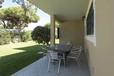a table and chairs on a patio with a yard at Vila Popa - Golf Front with Games Room by HD in Vilamoura