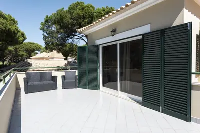 a patio with green shutters on a house at Vila Popa - Golf Front with Games Room by HD in Vilamoura
