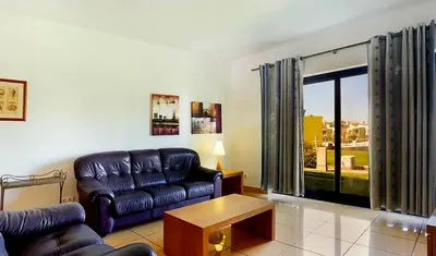 a living room with a leather couch and a table at Charming Orada 2-Bedroom Albufeira Duplex Apartment with Shared Pool sleeps 6 in Albufeira
