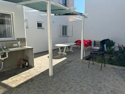 a covered patio with a table and a table and chairs at Casa do Outeiro - T2 Quarteira velha in Quarteira