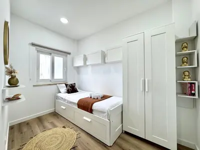a white bedroom with a bed and a window at Albufeira Shine by Homing in Albufeira