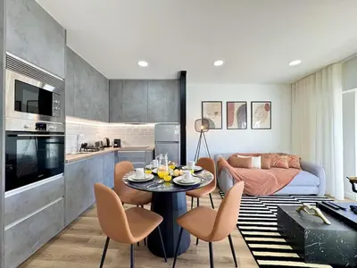 a kitchen and a living room with a table and chairs at Albufeira Shine by Homing in Albufeira