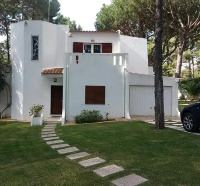 a white house with a tree in the yard at Villapinheiros in Vilamoura