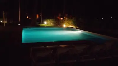 an empty swimming pool at night with lights at Villapinheiros in Vilamoura