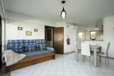 a living room with a bed and a table and chairs at Vilamoura central by HD in Vilamoura