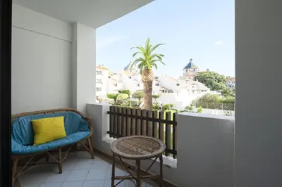 a balcony with two chairs and a palm tree at Vilamoura central by HD in Vilamoura