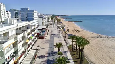 a view of a beach with buildings and palm trees at Quarteira Central 3 by Homing in Quarteira