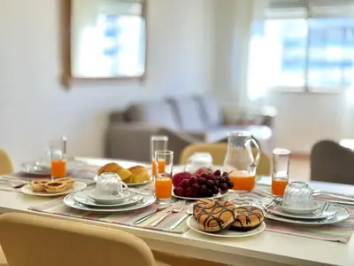 a table with plates of food and glasses of orange juice at Quarteira Central 3 by Homing in Quarteira