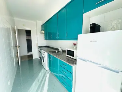 a kitchen with blue cabinets and a white refrigerator at Blue Apartament in Albufeira