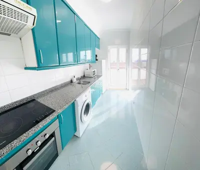 a kitchen with blue cabinets and a washing machine at Blue Apartament in Albufeira