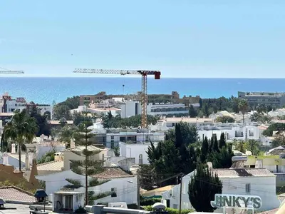a city with a crane and buildings and the ocean at Apartamento 5 estrelas praia da oura in Albufeira