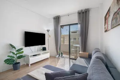 a living room with a couch and a tv at Abertura Mar Zen in Quarteira