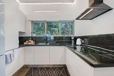 a kitchen with white cabinets and black counter tops at Bento Box Villa Family Hub Fitness in Vilamoura