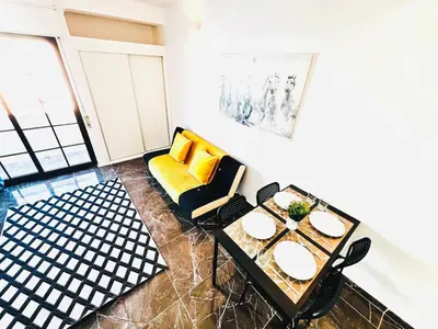 a living room with a yellow couch and a table at Studio com vista para Rua da Oura - Albufeira in Albufeira