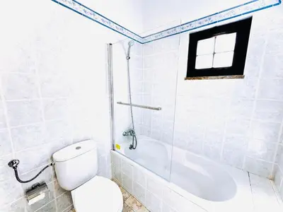 a bathroom with a toilet and a tub and a window at Studio com vista para Rua da Oura - Albufeira in Albufeira