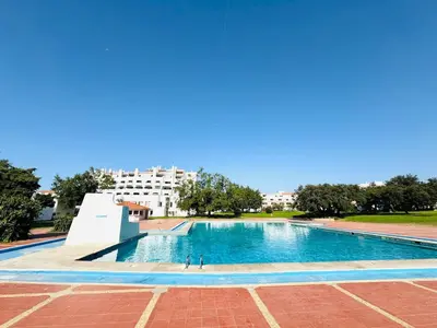 a swimming pool in a park with a building in the background at Apartamento aconchego T1 Rua da Oura in Albufeira
