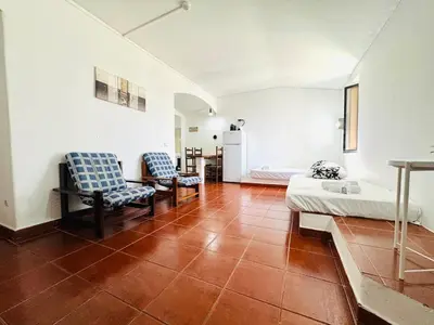 a living room with two chairs and a refrigerator at Apartamento aconchego T1 Rua da Oura in Albufeira