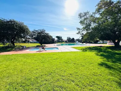 a group of people standing around a swimming pool in a park at Apartamento albufeira T1 condominio vila nova in Albufeira