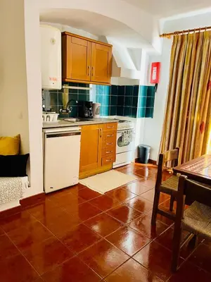 a kitchen with wooden cabinets and a tile floor at Resort Albufeira T1, Oura Beach in Albufeira