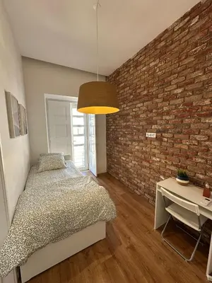 a bedroom with a bed and a brick wall at Casa das Oliveiras in Faro