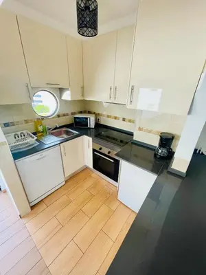 a kitchen with white cabinets and a wooden floor at Duplex Apartment Albufeira in Albufeira