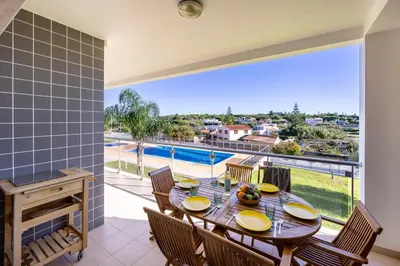 a dining room with a table and chairs and a large window at Almargem Apartment in Quarteira