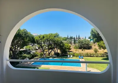 an arched window with a view of a swimming pool at The Sun of Quarteira in Quarteira