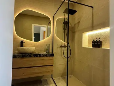 a bathroom with a shower with a round mirror at The Sun of Quarteira in Quarteira