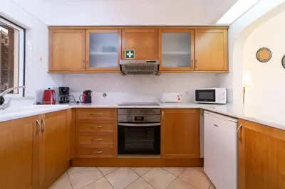 a kitchen with wooden cabinets and a stove top oven at My Inzu by HelloVacations in Albufeira