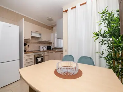 a kitchen with a table with chairs and a refrigerator at Akisol Albufeira Orion in Albufeira