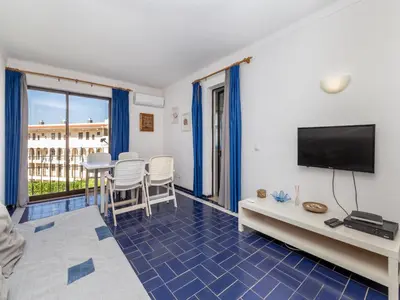 a living room with a tv and a table and chairs at Akisol Albufeira Eris in Albufeira