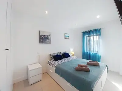 a white bedroom with a bed with blue sheets at Panorama Old Town sea view Albufeira in Albufeira