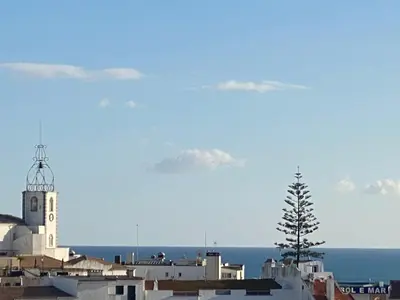 a building with a tower and a tree in front of the ocean at Panorama Old Town sea view Albufeira in Albufeira