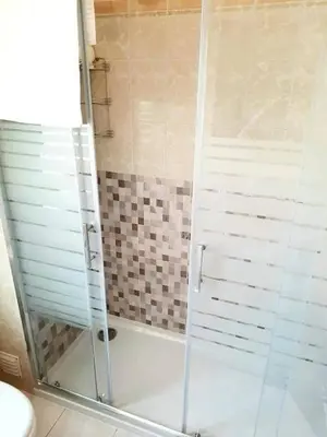 a shower with a glass door in a bathroom at Casa de Praia dos Avós in Quarteira