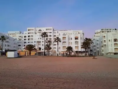 a large white building with palm trees in front of it at Casa de Praia dos Avós in Quarteira