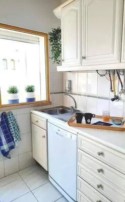 a kitchen with white cabinets and a sink and a window at Casa de Praia dos Avós in Quarteira