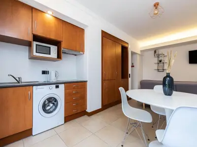 a kitchen with a white table and a washing machine at Akisol Vilamoura Iron in Quarteira