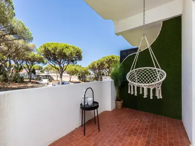 a porch with a swing hanging from a white fence at Akisol Vilamoura Iron in Quarteira