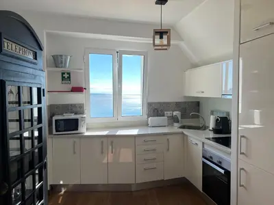 a kitchen with white cabinets and a window at casa do cesar in Albufeira