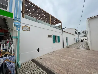 a white building with blue windows on a street at casa do cesar in Albufeira