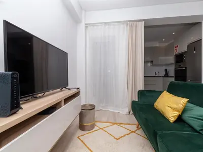 a living room with a green couch and a flat screen tv at Akisol Faro Virtuous in Faro