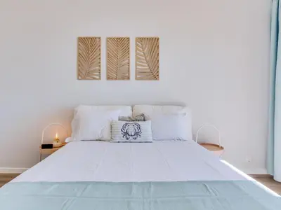 a white bedroom with a large bed with white sheets at Apartamento Vida Pura com 2 quartos e vista mar in Quarteira