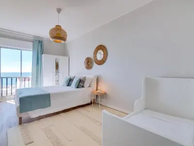 a white bedroom with a bed and a clock on the wall at Apartamento Vida Pura com 2 quartos e vista mar in Quarteira