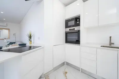 a white kitchen with white cabinets and a sink at Talia Lux - two-bedroom luxury apartment by HD in Vilamoura