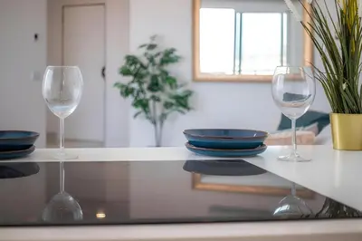 three wine glasses sitting on a counter with plates and bowls at Talia Lux - two-bedroom luxury apartment by HD in Vilamoura