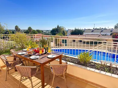 a wooden table and chairs on a patio with a pool at Balaia Poolside House with Sea View by BeCherish in Atalaia