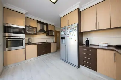 a large kitchen with wooden cabinets and a refrigerator at ABF38, encantadora Villa V4 em lugar sossegado in Guia