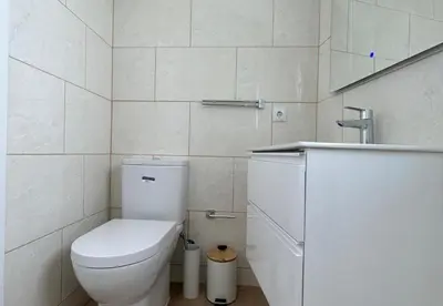 a white bathroom with a toilet and a sink at Playa Vista guest house in Albufeira