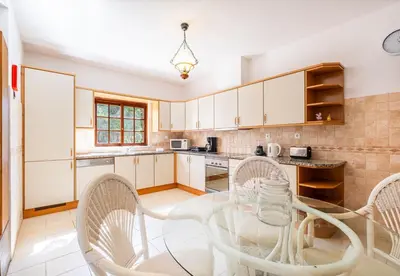 a kitchen with white cabinets and a table and chairs at Villa Retiro no Campo in Guia