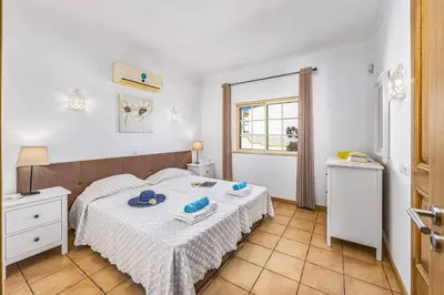 a bedroom with a bed with a table and a window at Villa Ventura by Villa Plus in Albufeira